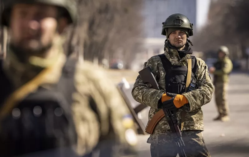 Ukrainian servicemen stand guard at a military check point in Kyiv on March 21, 2022. - At least eight people are killed in the bombing of a shopping centre in northwest Kyiv today. The 10-storey building is completely destroyed in the blast. Russia claims the mall was used to store rocket systems. (Photo by FADEL SENNA / AFP)