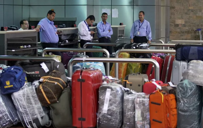 Egyptian airport labourers stand next to the luggage of tourists at the departure terminal in Egypt's Red Sea resort of Sharm El-Sheikh on November 5, 2015. Britain and Ireland suspended air links on November 4, over concerns a Russian flight home from Sharm el-Sheikh that crashed may have been brought down by a bomb. AFP PHOTO / STR