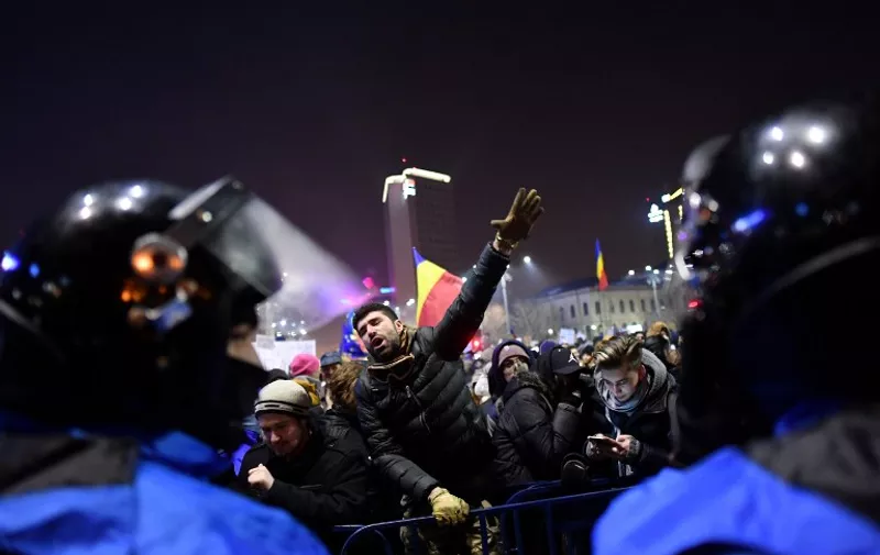 Romanian riot police stand guard as people demonstrate against controversial decrees to pardon corrupt politicians and decriminalize other offenses in front of the government headquarters in Bucharest, on February 1, 2017. 
At least 200,000 people hit the streets across Romania on February 1, 2017 for anti-government protests, the largest since communism fell in 1989, media reports said. / AFP PHOTO / DANIEL MIHAILESCU