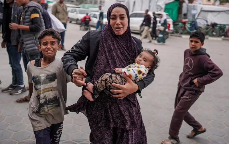 A Palestinian woman holding her children reacts outside a hospital where casualties are brought following Israeli bombardment in Bureij, central Gaza Strip, on April 8, 2024, as the war between Israel and the Hamas movement continues. (Photo by AFP)