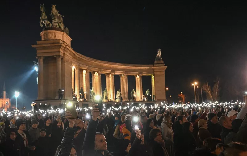 People light with their mobile phones as they demonstrate against Orban's government policies at the Heroes' Square in Budapest, Hungary on February 16, 2024. More than ten thousand people rallied on February 16 in Budapest responding to a controversy over a presidential pardon of a convicted child abuser's accomplice. Orban is facing his biggest political crisis since returning to power in 2010, following the shock resignations of two of his allies over a child sex abuse case. Hungary's President Novak and former Justice Minister Varga -- the ruling Fidesz party's most prominent women -- stepped down on February 10 over the pardoning of a convicted child abuser's accomplice. (Photo by ATTILA KISBENEDEK / AFP)