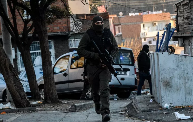 Turkish masked plain clothes police officer patrols a street during a clash between Kurdish activists and Turkish police  in the historical Sur district on December 24,2015 in Diyarbakir.
Turkish security forces are currently imposing curfews in five towns in the Kurdish-dominated southeast of Turkey in a bid to root out Kurdistan Workers Party (PKK) rebels from urban centres. In the town of Cizre in Sirnak province, which has been under curfew since early last week, 103 Kurdish militants have been killed. / AFP / ILYAS AKENGIN