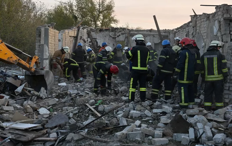 Ukrainian emergency personnel clear debris as they search for victims of a reported Russian strike which hit a shop and cafe in the village of Groza, some 30 kilometres west of Kupiansk, on October 5, 2023. A Russian strike on October 5, 2023 killed at least 51 people gathered for a wake in an eastern Ukrainian village in what a UN official called a "horrifying" attack. Footage published by the Ukrainian police showed a large area of smoking rubble and several bodies being taken away by emergency workers in the village of Groza. Ukrainian President said the strike had slammed into the Kupiansk district of the war-battered region bordering Russia, where Moscow's forces have been pushing to recapture territory they lost last year to Ukrainian troops. (Photo by SERGEY BOBOK / AFP)