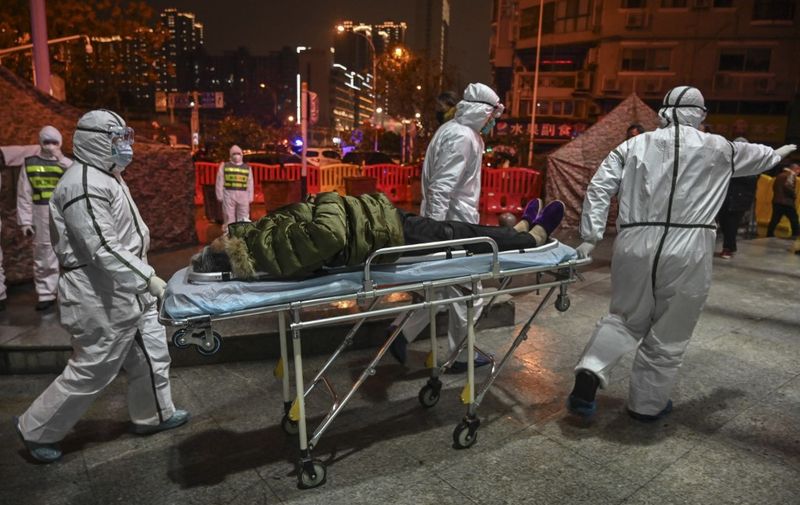 Medical staff members wearing protective clothing to help stop the spread of a deadly virus which began in the city, arrive with a patient at the Wuhan Red Cross Hospital in Wuhan on January 25, 2020. - The Chinese army deployed medical specialists on January 25 to the epicentre of a spiralling viral outbreak that has killed 41 people and spread around the world, as millions spent their normally festive Lunar New Year holiday under lockdown. (Photo by Hector RETAMAL / AFP)