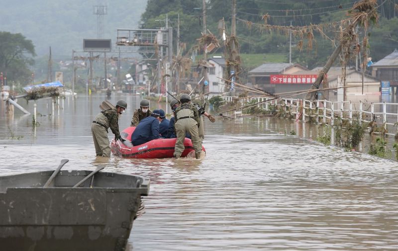 Japan Self-Defense Forces and police officers handle an inflatable boat to join rescue operations at a nursing home following heavy rain in Kuma village, Kumamoto prefecture, on July 5, 2020. - Two people died and 16 others were feared dead, local media said after torrential rain in western Japan triggered massive floods and mudslides. (Photo by STR / JIJI PRESS / AFP) / Japan OUT