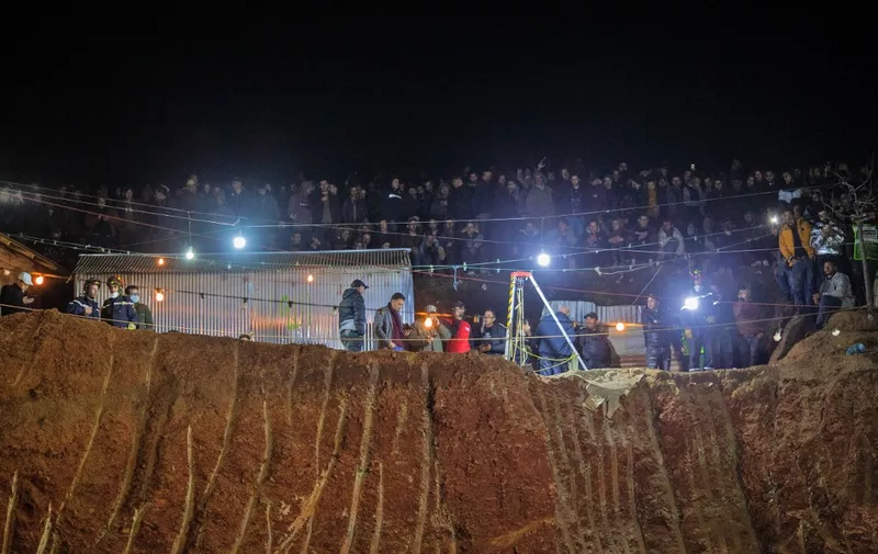 Bystanders watch as Moroccan authorities and firefighters work to rescue five-year-old boy Rayan, who is trapped in a deep well for over two days, near Bab Berred in Morocco's rural northern province of Chefchaouen on February 3, 2022. - Moroccans waited anxiously as authorities said a dramatic operation to rescue a young boy trapped in a deep well for more than 40 hours was nearing its end. (Photo by AFP)