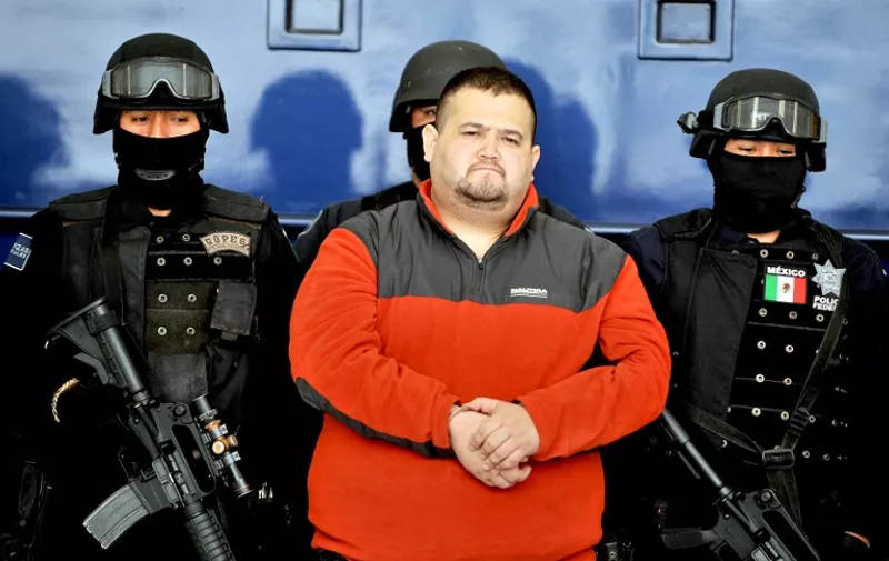 Eduardo Teodoro Garcia Simental, a.k.a "El Teo" (C), one of Mexico's most-wanted drug lords with possible connections to the Arellano Felix brothers or Tijuana cartels, is seen guarded by police officers in Mexico City on January 12, 2010. Garcia was captured early on January 12, 2010 in the northwestern state of Baja California Sur, Mexico, along with one of his brothers known as 'El Torito'. AFP PHOTO/Alfredo ESTRELLA / AFP / ALFREDO ESTRELLA