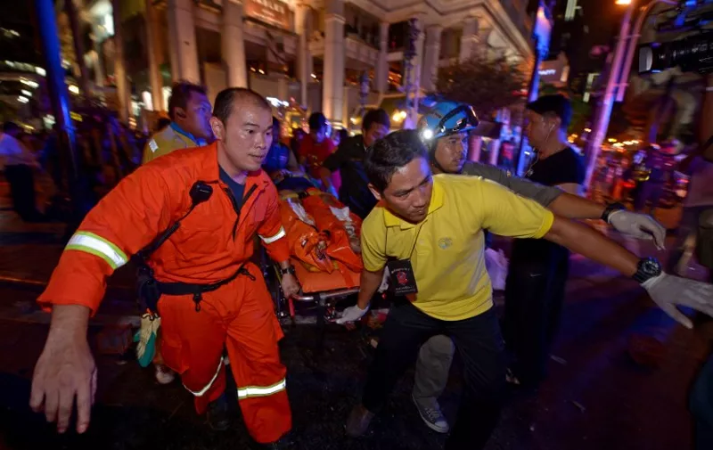 Thai rescue workers carry an injured person after a bomb exploded outside a religious shrine in central Bangkok late on August 17, 2015 killing at least 10 people and wounding scores more.  Body parts were scattered across the street after the explosion outside the Erawan Shrine in the downtown Chidlom district of the Thai capital.         AFP PHOTO / PORNCHAI KITTIWONGSAKUL