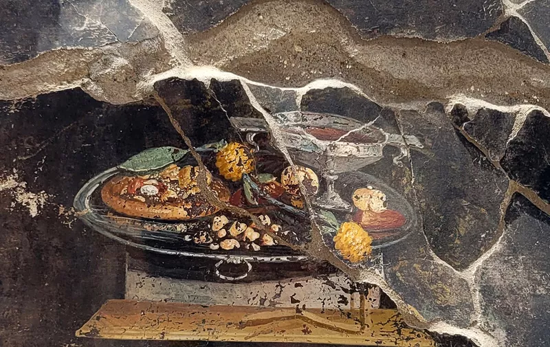 Discovery of a still life from the new excavations in Pompeii, Italy on June 2023. It looks like a pizza, on this Pompeian painting from 2000 years ago, but obviously it can't be, strictly speaking, given that some of the most characteristic ingredients were missing, namely tomatoes and mozzarella. However, as shown by an initial iconographic analysis of a fresco with still life, which has recently emerged as part of the new excavations in insula 10 of Regio IX in Pompeii, what was represented on the wall of an ancient Pompeian house could be a distant ancestor of the modern dish elevated to a World Heritage Site in 2017 as the ‘traditional art of the Neapolitan pizza maker. As the archaeologists of the Archaeological Park of Pompeii explain, it is assumed that next to a goblet of wine, placed on a silver tray, a flat focaccia is depicted which serves as a support for various fruits (identifiable a pomegranate and perhaps a date) , seasoned with spices or perhaps rather with a type of pesto (moretum in Latin), indicated by yellowish and ocher dots. Furthermore, present on the same tray, dried fruit and a garland of yellow strawberry trees, next to dates and pomegranates. Photo: (EV)/ ABACAPRESS.COM,Image: 785583232, License: Rights-managed, Restrictions: , Model Release: no