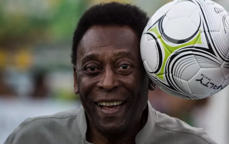 Legendary Brazilian former football player Pele poses with a ball during the inauguration ceremony of the new technology football pitch installed at Mineira favela in Rio de Janeiro, Brazil, on September 10, 2014. 200 self energy supplied  Pavegen panels, invented by British Laurence Kemball-Cook, were installed underground to capture kinetic energy created by the movement of the football players. The energy is stored and combined with solar panels' energy to illuminate the pitch during the night. The new technology pitch was created by oil giant Royal Dutch Shell.  AFP PHOTO / YASUYOSHI CHIBA
