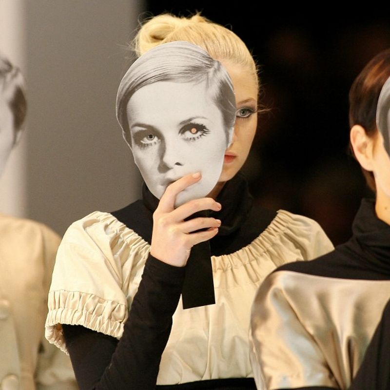 Models displaying cut out masks of former model 'Twiggy' parade outfits by Australian designers after a show during the Melbourne Fashion Festival, 05 March 2007.  Australia's top designers are parading their autumn/winter collection during the week long event.  AFP PHOTO/William WEST (Photo by WILLIAM WEST / AFP)