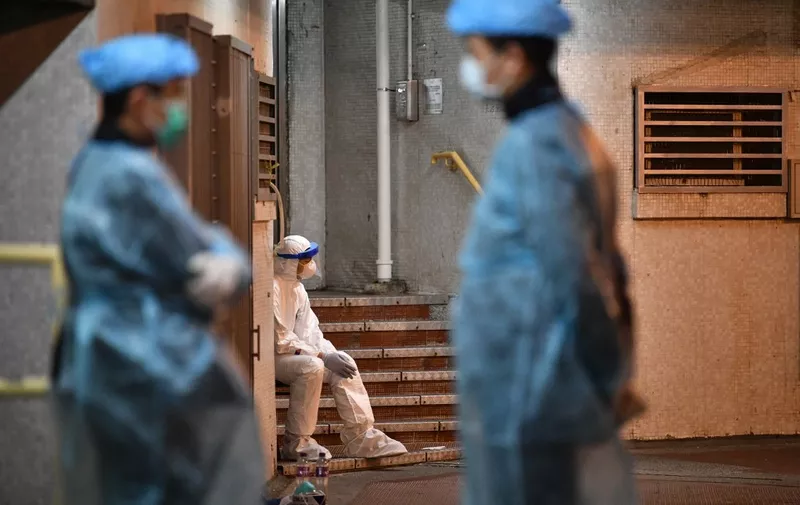 Medical personnel wearing protective suits stay near a block's entrance on the grounds of a residential estate in Hong Kong, early on February 11, 2020, after two people in the block were confirmed to have contracted the new coronavirus, according to local newspaper reports. (Photo by Anthony WALLACE / AFP)