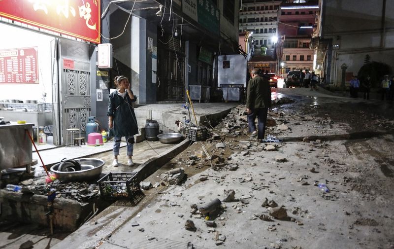 A woman stands outside a restaurant after a 5.0-magnitude earthquake in Qiaojia county, Zhaotong city, in China's southwestern Yunnan province early on May 19, 2020. - Four people were killed and another 23 injured when an earthquake shook southwestern China's Yunnan province, local authorities said on May 19. (Photo by STR / AFP) / China OUT
