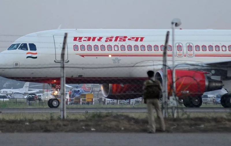 An Air India Airbus A320 taxis as a security serviceman looks on in the foreground at the Indira Gandhi International Airport in New Delhi on May 11, 2012. National carrier Air India May 11 suspended passenger bookings for flights to the United States, Europe and Canada because of a strike by pilots. The airline, which was already losing nearly $2 million a day, has been forced to cancel a number of international flights since its pilots began a wildcat strike by reporting in sick on Monday night.AFP PHOTO/RAVEENDRAN / AFP / RAVEENDRAN