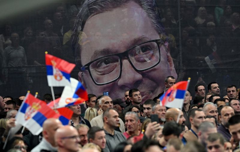 Supporters of the Serbian Progressive Party wave flags in front of a giant banner bearing a picture of Serbian President  Aleksandar Vucic during political rally of the Serbian Progressive Party (SNS) at the Stark Arena in Belgrade on December 2, 2023, ahead of the December 17 elections. Along with parliamentary elections, Serbian citizens will cast ballots in 65 municipalities, including the capital Belgrade.
During the last elections in April 2022, the SNS -- which has been in power since 2012 -- and coalition partners won 120 of the 250 seats in parliament. (Photo by Andrej ISAKOVIC / AFP)