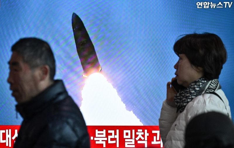 People walk past a television showing a news broadcast with file footage of a North Korean missile test, at a railway station in Seoul on March 18, 2024. North Korea fired a ballistic missile on March 18, Seoul's military said, as US Secretary of State Antony Blinken visited South Korea to meet top officials and attend a democracy summit. (Photo by Anthony WALLACE / AFP)