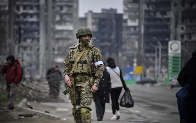 (FILES) In this file photo taken on April 12, 2022 a Russian soldier patrols in a street of Mariupol, as Russian troops intensify a campaign to take the strategic port city, part of an anticipated massive onslaught across eastern Ukraine, while Russia's President makes a defiant case for the war on Russia's neighbour. Throughout the spring of 2022 one city represented the horrific suffering and catastrophic destruction caused by the war in Ukraine: Mariupol. Large parts of the city on the Sea of Azov were razed to the ground during a brutal three-month siege. (Photo by Alexander NEMENOV / AFP)