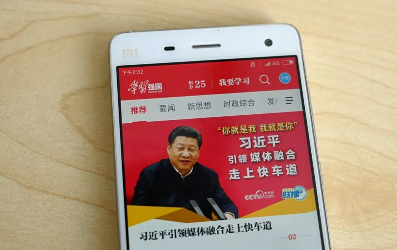 This photo illustratration taken on February 20, 2019 shows a phone app called "Xuexi Qiangguo" or "Study to make China strong" with an image of China's President Xi Jinping in Beijing. - A propaganda app that puts China's powerful President Xi Jinping in anyone's pockets has become a hit in the country -- with a helpful nudge from Communist Party officials. Xi, who could rule indefinitely after parliament lifted presidential term limits last year, has enjoyed a level of officially stoked adulation unseen since Communist China's founder Mao. (Photo by Greg Baker / AFP) / TO GO WITH China-politics-internet, FOCUS by Poornima WEERASEKARA