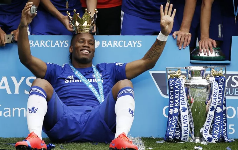 Chelsea's Ivorian striker Didier Drogba wears the crown holding a camera as he poses during the presentation of the Premier League trophy after the English Premier League football match between Chelsea and Sunderland at Stamford Bridge in London on May 24, 2015. Chelsea were officially crowned the 2014-2015 Premier League champions.  AFP PHOTO / ADRIAN DENNIS

RESTRICTED TO EDITORIAL USE. NO USE WITH UNAUTHORIZED AUDIO, VIDEO, DATA, FIXTURE LISTS, CLUB/LEAGUE LOGOS OR LIVE SERVICES. ONLINE IN-MATCH USE LIMITED TO 45 IMAGES, NO VIDEO EMULATION. NO USE IN BETTING, GAMES OR SINGLE CLUB/LEAGUE/PLAYER PUBLICATIONS.