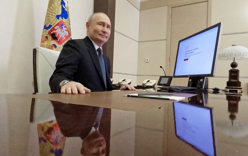 In this pool photograph distributed by Russia's state agency Sputnik, Russian President Vladimir Putin votes online in the presidential election at the Novo-Ogaryovo state residence, outside Moscow, on March 15, 2024. (Photo by Mikhail METZEL / POOL / AFP)