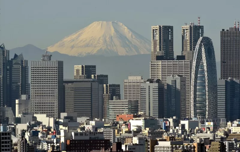 Japan's highest mountain, Mount Fuji at 3,776m (12,388 feet), is seen behind skyscrapers in Tokyo's Shinjuku area on November 28, 2015. Mount Fuji lies about 100 kilometres (60 miles) south-west of Tokyo, and can be seen from there on a clear day. AFP PHOTO / KAZUHIRO NOGI / AFP / KAZUHIRO NOGI