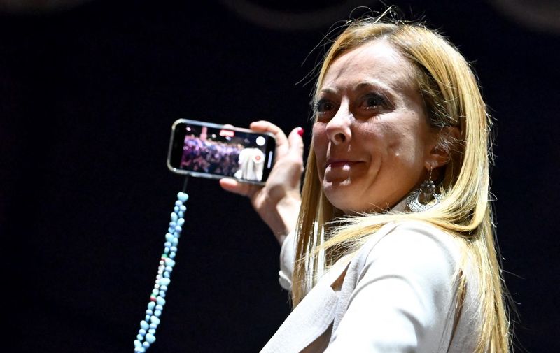 Brothers of Italy party leader Giorgia Meloni reacts as she takes a selfie video, after she delivered a speech on stage on September 22, 2022 during a joint rally of Italy's right-wing parties Brothers of Italy (Fratelli d'Italia, FdI), the League (Lega) and Forza Italia at Piazza del Popolo in Rome, ahead of the September 25 general election. (Photo by Alberto PIZZOLI / AFP)