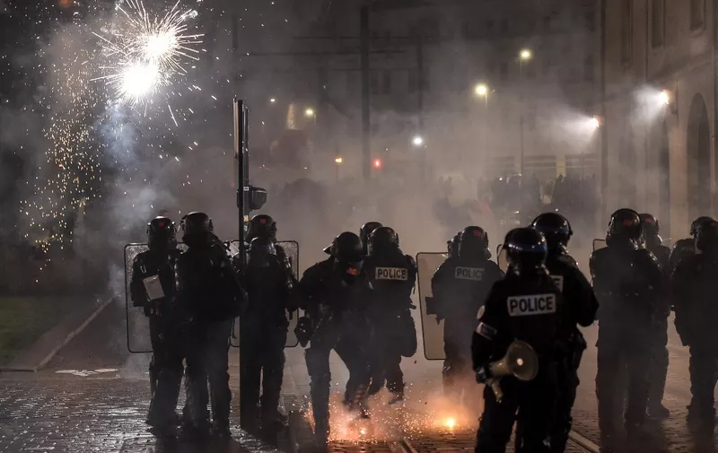 Protesters throws fireworks towards French riot police during a torchlight march on the fifth day of nationwide rallies organised since the start of the year, against a deeply unpopular pensions overhaul, in Nantes, western France, on February 16, 2023. (Photo by Sebastien SALOM-GOMIS / AFP)