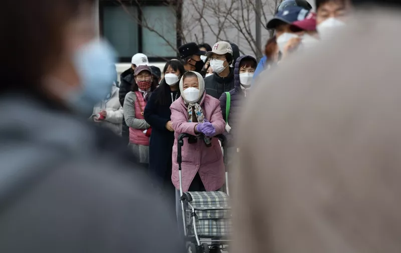 People wait in line to buy face masks from a post office near the Daegu branch of the Shincheonji Church of Jesus in Daegu on February 27, 2020. - The secretive South Korean religious group at the centre of the country's new coronavirus outbreak is a sprawling network so wealthy it can mobilise thousands of believers to hold Pyongyang-style mass performances at Seoul's Olympic stadium. More than half of the country's nearly 1,600 infections are linked to Shincheonji followers. (Photo by Jung Yeon-je / AFP)