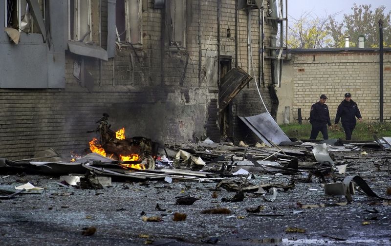 Police officers walk at the site of a car bomb explosion outside a building housing a local TV station in the Russian-held city of Melitopol in southern Ukraine on October 25, 2022. (Photo by STRINGER / AFP)