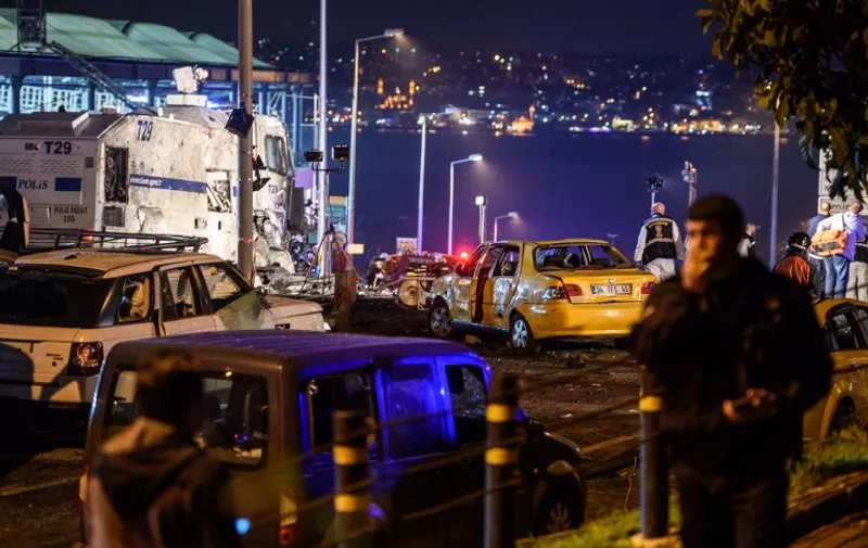 Turkish police officers and forensic work next to damaged police vehicles and cars on the site where a car bomb exploded near the stadium of football club Besiktas in central Istanbul on December 10, 2016. 
 The car bomb exploded in the heart of Istanbul on late December 10, wounding around 20 police officers, Turkey's interior minister said, quoted by the official Anadolu news agency. The bomb, apparently targeting a bus carrying police officers, exploded outside the stadium of Istanbul football club Besiktas following its match against Bursaspor. / AFP PHOTO / OZAN KOSE