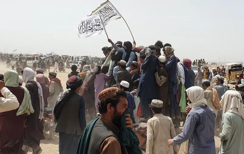 People wave Taliban flags as they drive through the Pakistani border town of Chaman on July 14, 2021, after the Taliban claimed they had captured the Afghan side of the border crossing of Spin Boldak along the frontier with Pakistan. (Photo by Asghar ACHAKZAI / AFP)