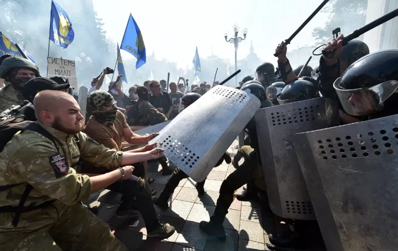 People try to pull shields away from officers as activists of radical Ukrainian parties, including the Ukrainian nationalist party Svoboda (Freedom), clash with police officers in front of the parliament in Kiev on August 31, 2015. At least 20 were wounded in clashes outside parliament in Kiev after lawmakers gave initial approval to constitutional changes granting more autonomy to pro-Russian separatists in eastern Ukraine. A loud blast was heard outside parliament shortly after the bill was passed, an AFP journalist said. Ukrainian interior ministry advisor and top lawmaker Anton Gerashchenko wrote on Facebook that attackers threw a hand grenade at National Guard troops guarding the building in what he called an "act of provocation." AFP PHOTO / SERGEI SUPINSKU