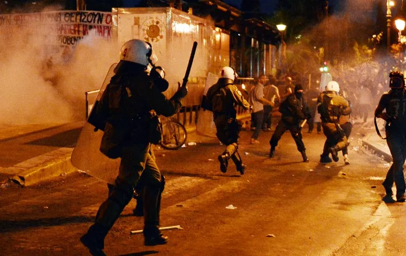 Protesters clash with riot police during an anti-austerity protest on July 15, 2015. Anti-austerity protesters hurled petrol bombs at police in front of Greece's parliament on July 15 as lawmakers began debating deeply unpopular reforms needed to unlock a new eurozone bailout.Riot police responded with tear gas against dozens of hooded protesters who set ablaze parts of Syntagma square in central Athens. AFP PHOTO/ LOUISA GOULIAMAKI