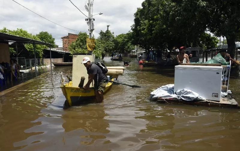 Locals try to recover belongings in a flooded neighbourhood in Asuncion on December 20, 2015. Constant and heavy rains in the country have caused the overflowing of the Paraguay river, leaving--up  to now-- 13,000 families affected by flooding, and violent protests outside government offices demanding state attention.   AFP PHOTO / NORBERTO DUARTE / AFP / NORBERTO DUARTE