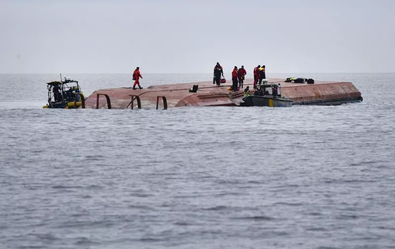 Divers and members of a sea rescue team work on the capsized Danish cargo ship Karin Hoej which collided with the British cargo ship Scot Carrier on the Baltic Sea between the Swedish city of Ystad and the Danish island of Bornholm, on December 13, 2021. - Two people were missing after the two cargo ships collided in the early morning hours, the Swedish Maritime Administration said. (Photo by Johan NILSSON / TT News Agency / AFP) / Sweden OUT