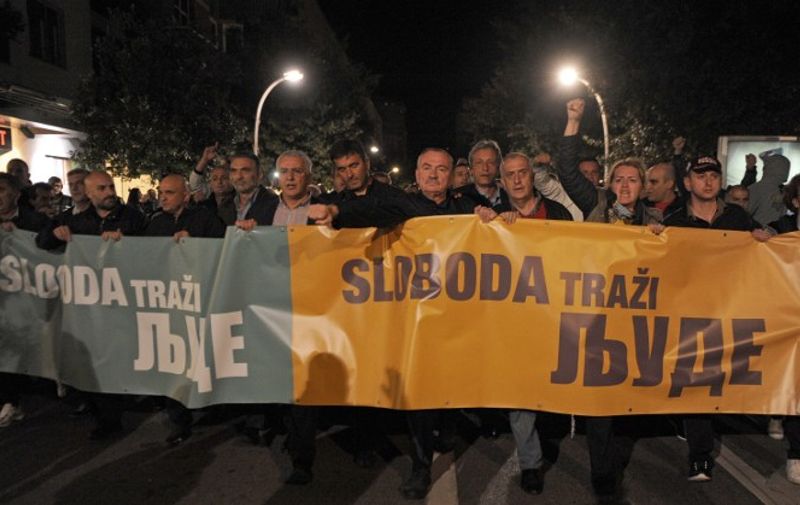 Montenegro's opposition protesters walk with a banner reading "People demands freedom" on October 17, 2015 in Podgorica. Montenegro's police used tear gas late Saturday to disperse a few hundred opposition protesters trying to rally here in front of the parliament despite a police ban. Several hundred officers sealed off key government institutions in downtown Podgorica preventing the protesters seeking resignation of Prime Minister Milo Djukanovic left-wing government, to approach the assembly.   AFP PHOTO / SAVO PRELEVIC