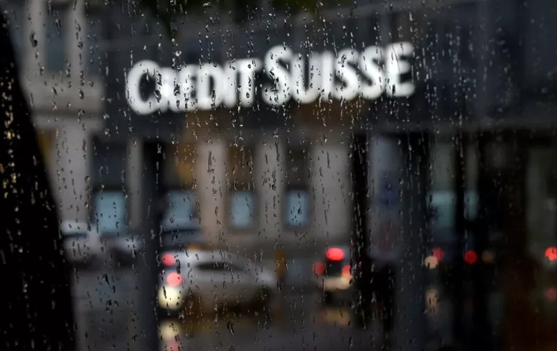 A picture taken on June 13, 2016 shows a branch of Swiss banking giant Credit Suisse behind a window under the rain, in Basel. / AFP PHOTO / FABRICE COFFRINI