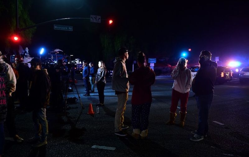 People stand and watch as the scene unfurls from the intersection of US 101 freeway and the Moorpark Rad exit as police vehicles close off the area outside a country music bar and dance hall in Thousand Oaks, west of Los Angeles, where a gunman opened fire late November 7, 2018, killing at least 12 people, US police said. (Photo by Frederic J. BROWN / AFP)