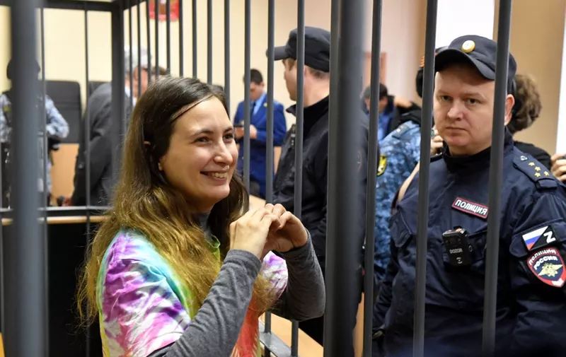 Russian artist Alexandra Skochilenko, 33, accused of spreading disinformation about the Russian army for changing supermarket price tags with messages criticising Russia's military offensive in Ukraine, gestures from inside a defendants' cage during her verdict hearing at a court in Saint Petersburg on November 16, 2023. (Photo by Olga MALTSEVA / AFP)