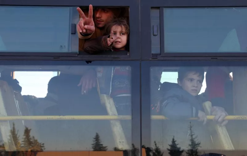 Syrians, who were evacuated from rebel-held neighbourhoods in the embattled city of Aleppo, gesture as they arrive in the opposition-controlled Khan al-Aassal region, west of the city, on December 15, 2016, the first stop on their trip, where humanitarian groups will transport the civilians to temporary camps on the outskirts of Idlib and the wounded to field hospitals.
Hundreds of civilians and rebels left Aleppo under an evacuation deal that will allow Syria's regime to take full control of the city after years of fighting. / AFP PHOTO / Baraa Al-Halabi