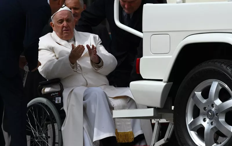 Pope Francis speaks with his aides prior to being helped get up the popemobile car from his wheelchair, as he leaves on March 29, 2023 at the end of the weekly general audience at St. Peter's square in The Vatican. - Pope Francis has been at the Gemelli Hospital in Rome since the afternoon of March 29, 2023 for some previously scheduled check-ups, the Holy See press director said. (Photo by Vincenzo PINTO / AFP)