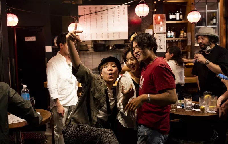 People pose as they gather at an "izakaya", or Japanese-style bar, in Tokyo on late May 27, 2020, after the Japanese government lifted a state of emergency due to the COVID-19 coronavirus. (Photo by Behrouz MEHRI / AFP)
