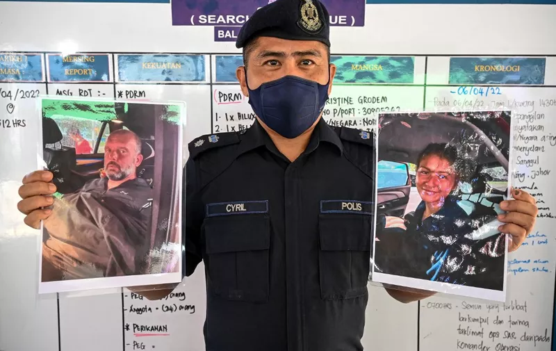 Mersing district police chief Cyril Edward shows pictures of two divers found alive, French national Alexia Alexandra Molina (R) and British national Adrian Peter Chesters (L), with a Dutch teen still missing, after a press conference in Mersing on April 9, 2022, during the search to locate three divers at sea after they went missing off Malaysia's southeast coast near Mersing in Johor state. (Photo by Mohd RASFAN / AFP)