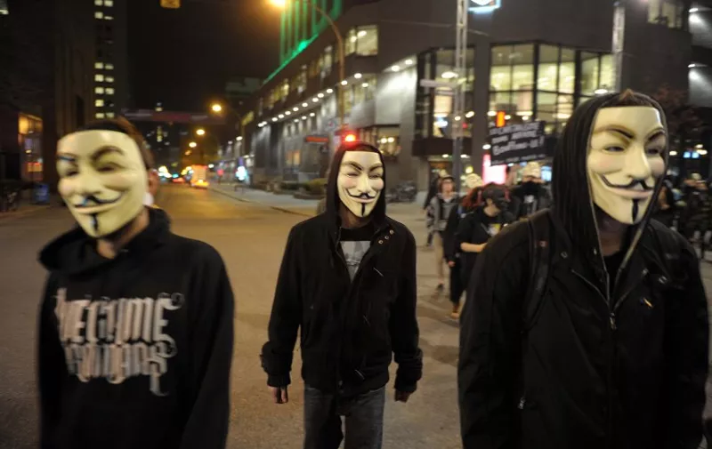 Canada, Montréal  : protesters wearing Guy Fawkes masks hold placards as they congregate in Victoria square ahead of the &quot;Million Masks March&quot;, organised by the group Anonymous, in Montréal downtown on November 5, 2015. The protest was held on the night  , and many of the marchers wore the white masks of Anonymous.
photos : KADRI MOHAMED/ imagespic.com (Photo by Mohamed Kadri/NurPhoto)