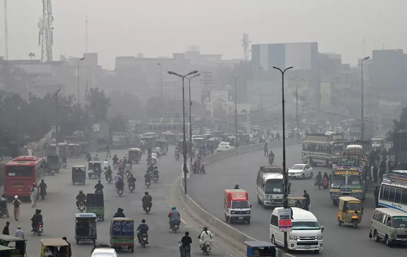 Commuters make their way through a busy street amid smoggy conditions in Lahore on November 7, 2023. (Photo by Arif ALI / AFP)
