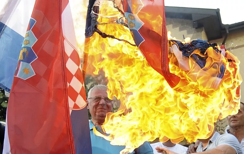 Serbian nationalist leader Vojislav Seselj (C) burns the Croatian national flag in front of the Croatian embassy during a protest in Belgrade on August 5, 2015. Zagreb cheered and Belgrade wept as they marked the 20th anniversary of Operation Storm, which ended the war sparked by Croatia's proclamation of independence from Yugoslavia and caused an exodus of Croatian Serbs. AFP PHOTO / ALEXA STANKOVIC