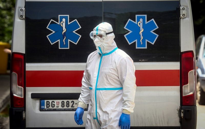 A medical worker stands in front of an ambulance at the Clinic for Infectious and Tropical Diseases in Belgrade on June 24, 2020, as the number of coronavirus (COVID-19) cases grow again in Serbia. - Serbia officially confirmed on June 24, 2020, a total of 13,235 cases of the coronavirus (143 more than Tuesday). Out of that number a total of 263 have died. (Photo by Oliver BUNIC / AFP)