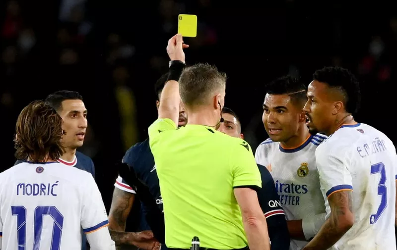 Italian referee Daniele Orsato shows a yellow card to Real Madrid's Brazilian midfielder Casemiro (2R) during the UEFA Champions League round of 16 first leg football match between Paris Saint-Germain (PSG) and Real Madrid at the Parc des Princes stadium in Paris on February 15, 2022. (Photo by FRANCK FIFE / AFP)