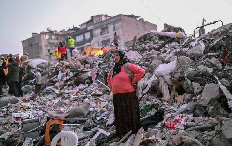 A woman stands in the rubble hoping her relatives to be found by rescuers in Hatay on February 13, 2023, as rescue teams began to wind down the search for survivors today, a week after an earthquake devastated parts of Turkey and Syria leaving more than 35,000 dead and millions in dire need of aid. (Photo by BULENT KILIC / AFP)