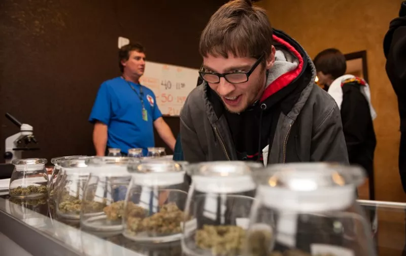 DENVER, CO - JANUARY 1: Tyler Williams of Blanchester, Ohio selects marijuana strains to purchase at the 3-D Denver Discrete Dispensary on January 1, 2014 in Denver, Colorado. Legalization of recreational marijuana sales in the state went into effect at 8am this morning.   Theo Stroomer/Getty Images/AFP